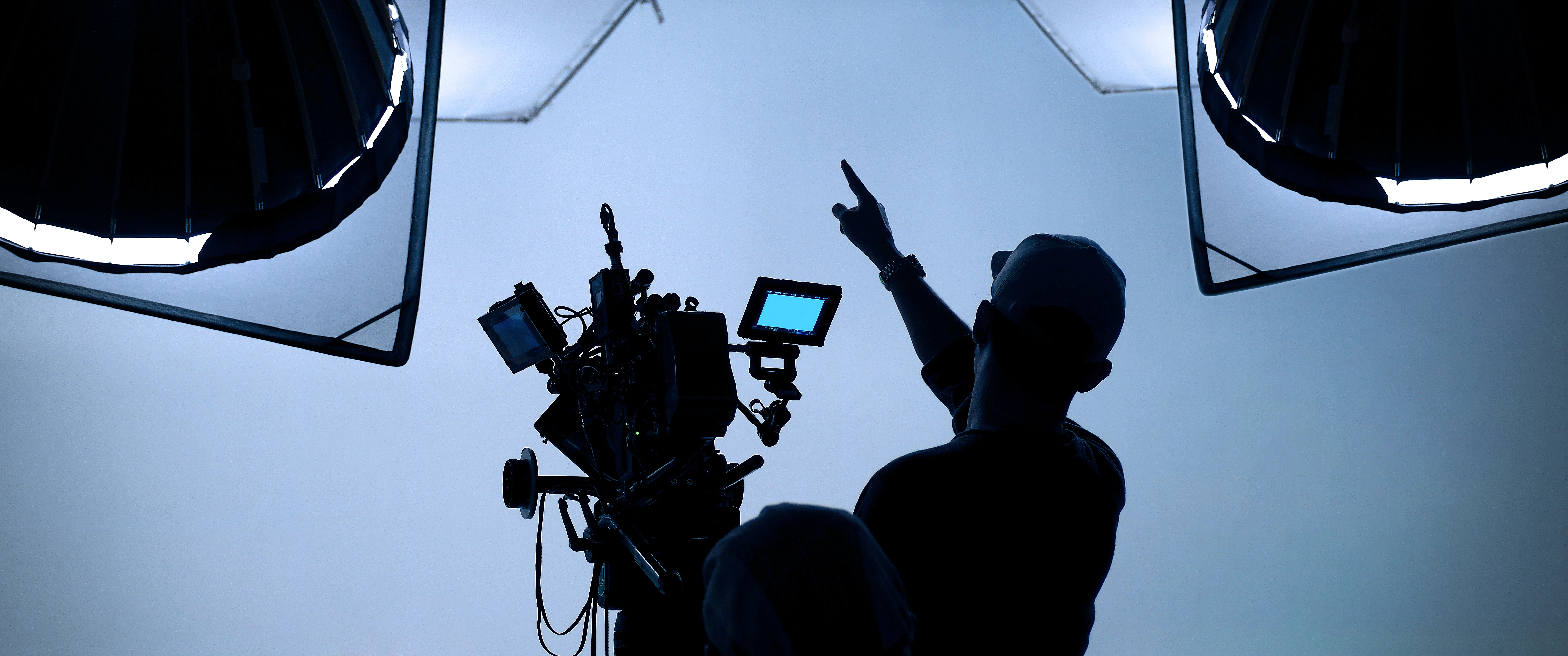 A camera operator on a lit studio set, signalling to the crew
